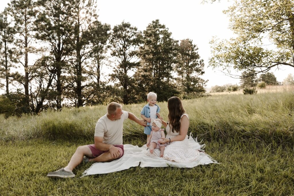 family of 4 on a blanket with tree behind them