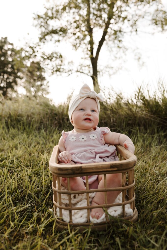 little 6 month old sitting in a basket smiling at mom and dad