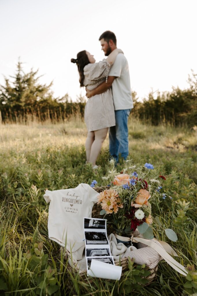 onesie & ultrasound in a basket with couple in back