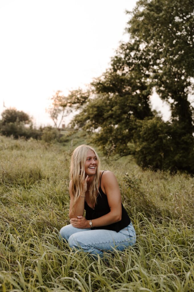 senior posing for a picture, squatted down look off to the side