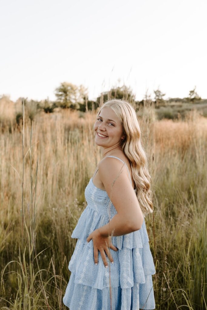 senior girl posing for a photographer in a feild