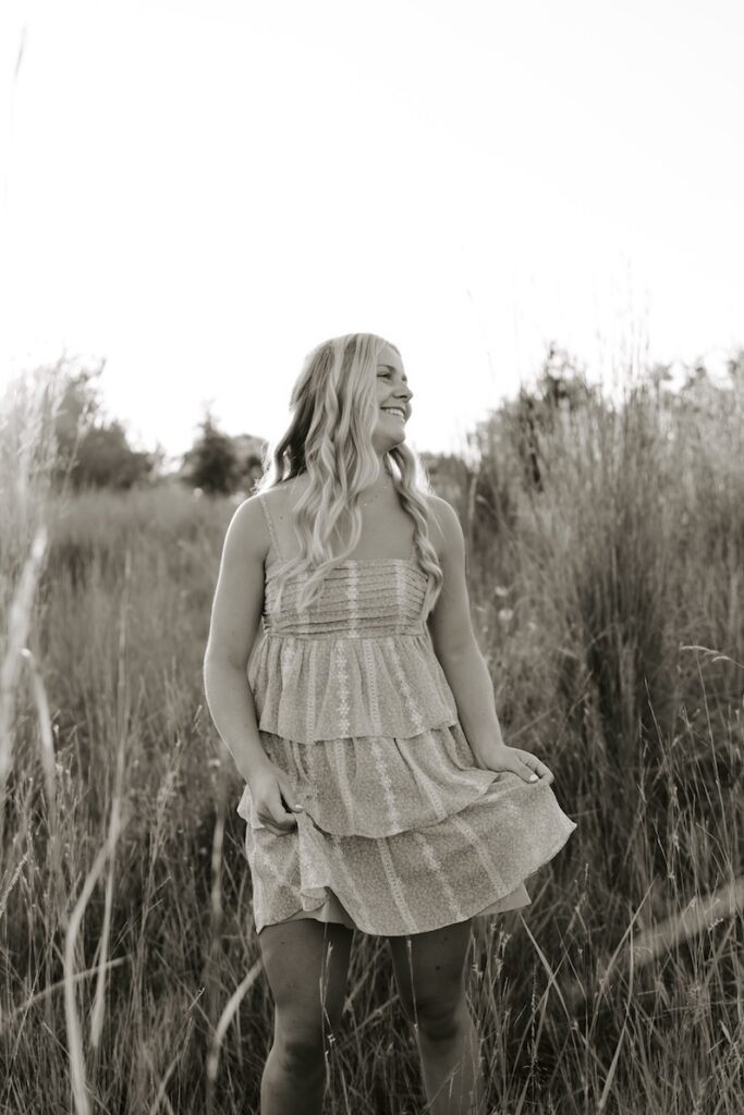 senior girl posing for a photographer in a feild