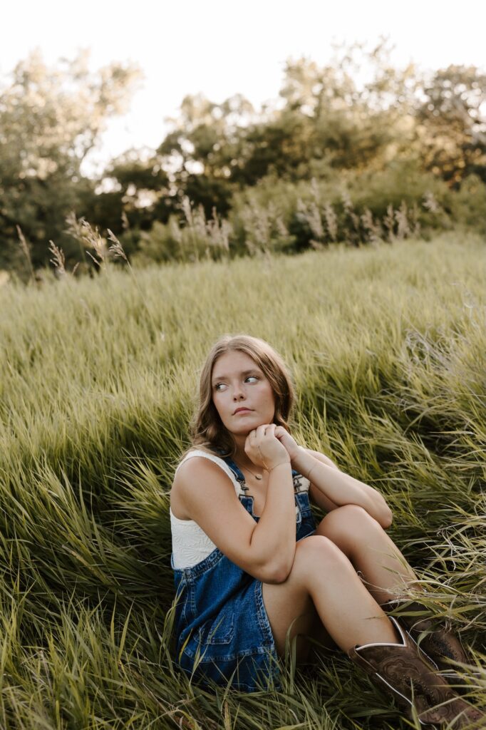 senior girl posing for a photographer in a feild