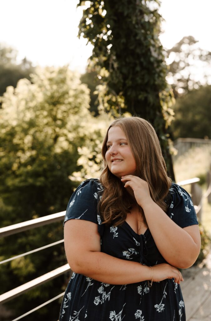 senior girl posing for a photographer in a feild