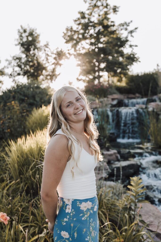 senior girl posing for a photographer in a feild