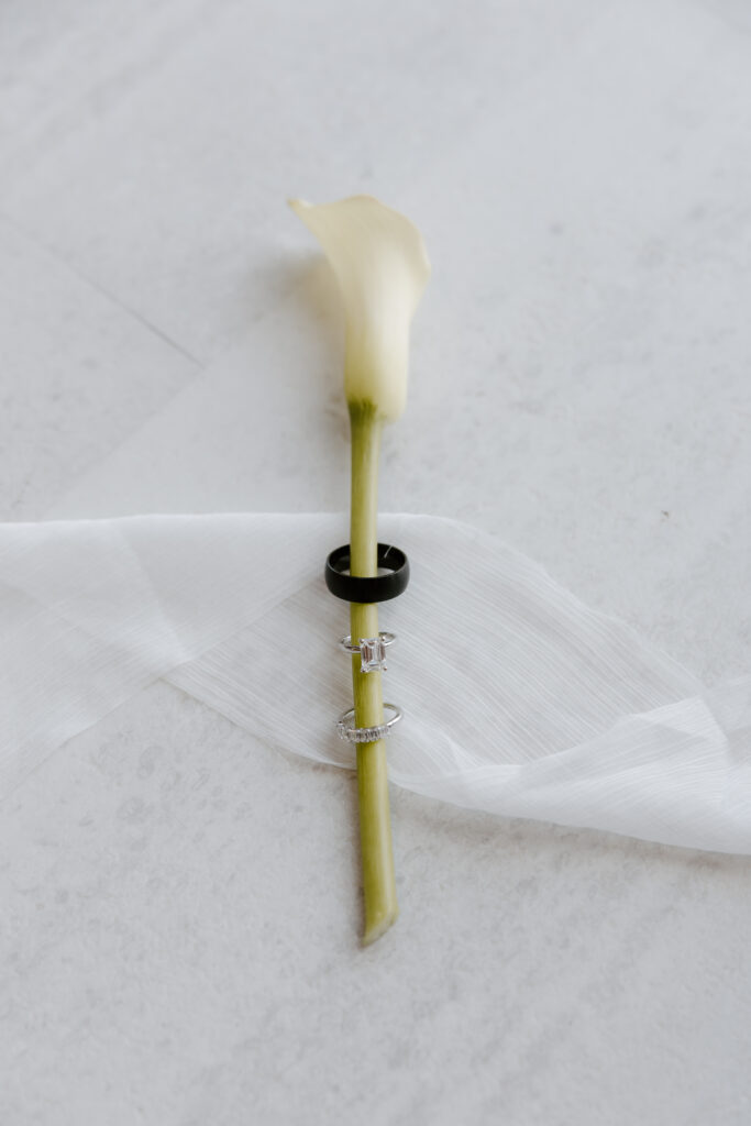 photograph of a calla lille with wedding rings on it